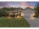 Charming single-story home with a Spanish tile roof, lush lawn, and mature landscaping at sunset at 11497 Sw 82Nd Court Rd, Ocala, FL 34481