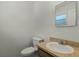 Bright bathroom featuring a toilet, vanity, mirror and natural light, with neutral-colored walls at 11987 Se 95Th Ter, Belleview, FL 34420