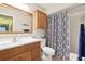 Well-lit bathroom featuring a wood vanity, toilet, and tub with a patterned shower curtain at 1202 Bly Ct, Eustis, FL 32726