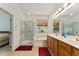 Bathroom featuring wood cabinets, dual vanity, soaking tub, and large glass shower at 12511 Se 91St Terrace Rd, Summerfield, FL 34491