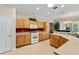 Bright kitchen featuring wooden cabinetry, white appliances, and tile flooring at 12511 Se 91St Terrace Rd, Summerfield, FL 34491