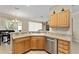 Functional kitchen with wood cabinetry, stainless steel dishwasher, and breakfast bar at 12511 Se 91St Terrace Rd, Summerfield, FL 34491