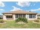 Back of house with sunroom and small landscaped yard, nice grass and manicured shrubs at 12511 Se 91St Terrace Rd, Summerfield, FL 34491