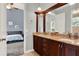 Bathroom with wood cabinets, granite counters, dual sinks, and view to connected bedroom at 13112 Luntz Point Ln, Windermere, FL 34786