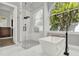 Bright bathroom features a glass-enclosed shower and modern soaking tub beneath a large arched window at 13112 Luntz Point Ln, Windermere, FL 34786