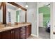 Bathroom with wood cabinets, granite counters, dual sinks, and view to connected bedroom at 13112 Luntz Point Ln, Windermere, FL 34786