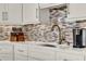 Kitchen boasts white cabinets, quartz countertops, mosaic tile backsplash, and stainless steel appliances at 13112 Luntz Point Ln, Windermere, FL 34786