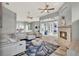 Open-concept living room featuring a stone fireplace, large windows, ceiling fans, and view into the kitchen at 13112 Luntz Point Ln, Windermere, FL 34786