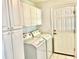 Convenient laundry room with cabinets, full-size washer, dryer, and an exterior access door at 1312 Corona Ave, The Villages, FL 32159