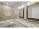 Bathroom featuring double sink vanity with stone countertops, tile accent wall, and bathtub shower combo at 137 E Palmetto Ave, Howey In The Hills, FL 34737