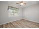 Bright bedroom features wood-look flooring, ceiling fan, and a window providing natural light and neighborhood views at 137 E Palmetto Ave, Howey In The Hills, FL 34737