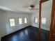 Bright bedroom with three windows, dark wood floor, and ceiling fan at 1425 Douglas Rd, Groveland, FL 34736
