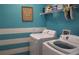Bright laundry room with white washer and dryer, blue walls with white stripes, and shelving with cleaning supplies at 146 Essex Pl, Davenport, FL 33896