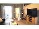 Bright living area with a large TV, stylish shelving, and sliding glass doors leading to the backyard at 146 Essex Pl, Davenport, FL 33896