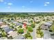 Aerial view of a neighborhood with well-maintained landscaping, mature trees and a lush green golf course nearby at 1561 Loris Loop, The Villages, FL 32162