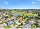 Aerial view of house with golf course and pond in the background of a beautiful, well-manicured neighborhood at 1561 Loris Loop, The Villages, FL 32162