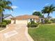 Charming home with a well-manicured lawn, beautiful landscaping, and an inviting patterned driveway to its 2-car garage at 1561 Loris Loop, The Villages, FL 32162
