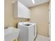 Functional laundry room with a white washer and dryer set, sink, and ample overhead cabinet storage at 1561 Loris Loop, The Villages, FL 32162