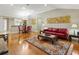 This open living room features hardwood floors, a red sofa, and an adjacent dining area at 1561 Loris Loop, The Villages, FL 32162