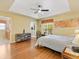 Main bedroom with wood laminate flooring, a tray ceiling, and ensuite access at 1561 Loris Loop, The Villages, FL 32162