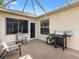 Inviting screened patio area with comfortable seating and grill, perfect for outdoor entertaining at 1561 Loris Loop, The Villages, FL 32162