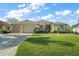 Charming home showcasing a well-manicured lawn, mature landscaping, and a circular driveway for convenient access at 1723 Carrera Dr, The Villages, FL 32159
