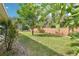 Beautiful backyard featuring lush lawn, brick wall, landscaping, and mature trees at 179 Patrice Hope St, Leesburg, FL 34748