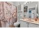 Bathroom with floral shower curtain, framed mirror, vanity with pink sink, and cabinet storage at 1917 Peachtree Ave, The Villages, FL 32162