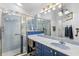 Classic bathroom featuring a walk-in shower with glass doors, blue vanity, and decorative lighting at 1917 Peachtree Ave, The Villages, FL 32162