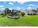 The landscaped backyard includes stone retaining walls, a lawn, and screened patio at 1992 Hagood Loop, The Villages, FL 32162