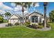 Beautiful home with lush landscaping, mature palm trees, and a paver driveway at 1992 Hagood Loop, The Villages, FL 32162