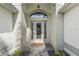 Elegant glass front door with decorative sidelights and transom, set in an arched entryway at 1992 Hagood Loop, The Villages, FL 32162