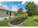 Lush backyard landscaping with decorative mulch beds, a well-maintained lawn, and mature shade trees at 1992 Hagood Loop, The Villages, FL 32162