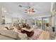 Bright living room with a ceiling fan, light wood floors, and sliding glass doors to the outside at 1992 Hagood Loop, The Villages, FL 32162
