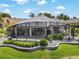 Beautiful outdoor screened lanai with covered seating area and meticulously landscaped yard at 1992 Hagood Loop, The Villages, FL 32162