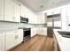 This kitchen showcases modern, white cabinets, stainless steel appliances, light backsplash, and stunning hardwood flooring at 2261 Osprey Ave, Orlando, FL 32814