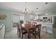 Dining area with a dark wood table, chandelier, and slider to the outdoor space with kitchen view at 2471 Yalaha Ave, The Villages, FL 32162