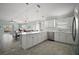 Open kitchen with white cabinets, tile backsplash, and a large island overlooking the living space at 2471 Yalaha Ave, The Villages, FL 32162