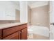 Bathroom featuring a vanity with granite countertop, cherry wood cabinets and tub with tile surround at 251 Blue Cypress Dr, Groveland, FL 34736