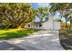 Home with a long driveway leading up to a home with a white brick exterior and chimney, shaded by trees at 2517 Royal Palm Dr, Edgewater, FL 32141