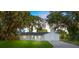 Charming single-story home with a white brick exterior, green lawn, and mature trees draped in Spanish moss at 2517 Royal Palm Dr, Edgewater, FL 32141