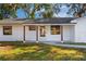 Inviting front porch of a white brick home, features stained wood columns, a glass front door, and manicured lawn at 2517 Royal Palm Dr, Edgewater, FL 32141