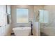 Bright bathroom features a soaking tub beneath a window and a glass-enclosed shower with marble-style tiling at 25962 High Hampton Cir, Sorrento, FL 32776