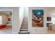 Hallway view of staircase with vibrant art and a glimpse into the living area and kitchen beyond at 25962 High Hampton Cir, Sorrento, FL 32776
