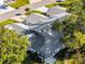 Overhead view of a well-maintained home showcasing a gray roof surrounded by lush trees in a quiet neighborhood at 26032 Newcombe Cir, Leesburg, FL 34748