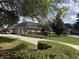 Brick home with a two-car garage, mature trees and manicured hedges on a well-maintained lawn at 2756 Sequoyah Dr, Haines City, FL 33844
