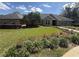 Manicured lawn and red flowering shrubs line the walkway to the brick home with large front windows at 2756 Sequoyah Dr, Haines City, FL 33844