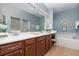 Bathroom with double vanity sinks, tile floors, and a separate soaking tub with white tile surround at 3048 New Haven Pl, Mount Dora, FL 32757