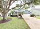 Charming blue home featuring a two-car garage, beautiful landscaping, and a well-manicured lawn at 3275 Oak Brook Ln, Eustis, FL 32736
