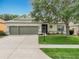 Charming single-story home featuring a manicured lawn, mature trees, and a three-car garage at 3551 Mulberry Grove Loop, Leesburg, FL 34748